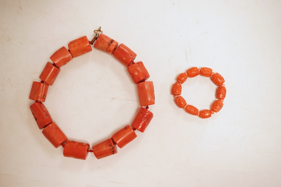 Two coral bead necklaces, one composed of large cylindrical coral beads, approximately 2.5-3.5cm each, total length 49cm; and a bracelet composed of carved coral beads spaced by smaller pink coral beads, on an elasticate